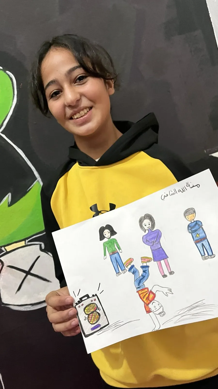 Student displaying her creative drawing of people at the Colors of Hope art therapy session